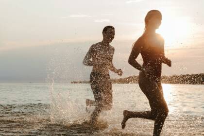 Teenagers running on the beach at sunset, enjoying vacation by the seaside.