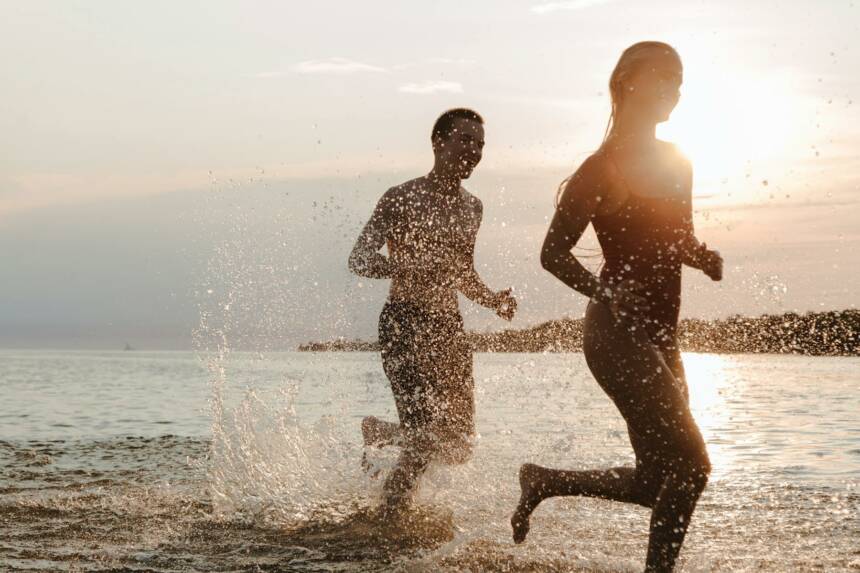 Teenagers running on the beach at sunset, enjoying vacation by the seaside.